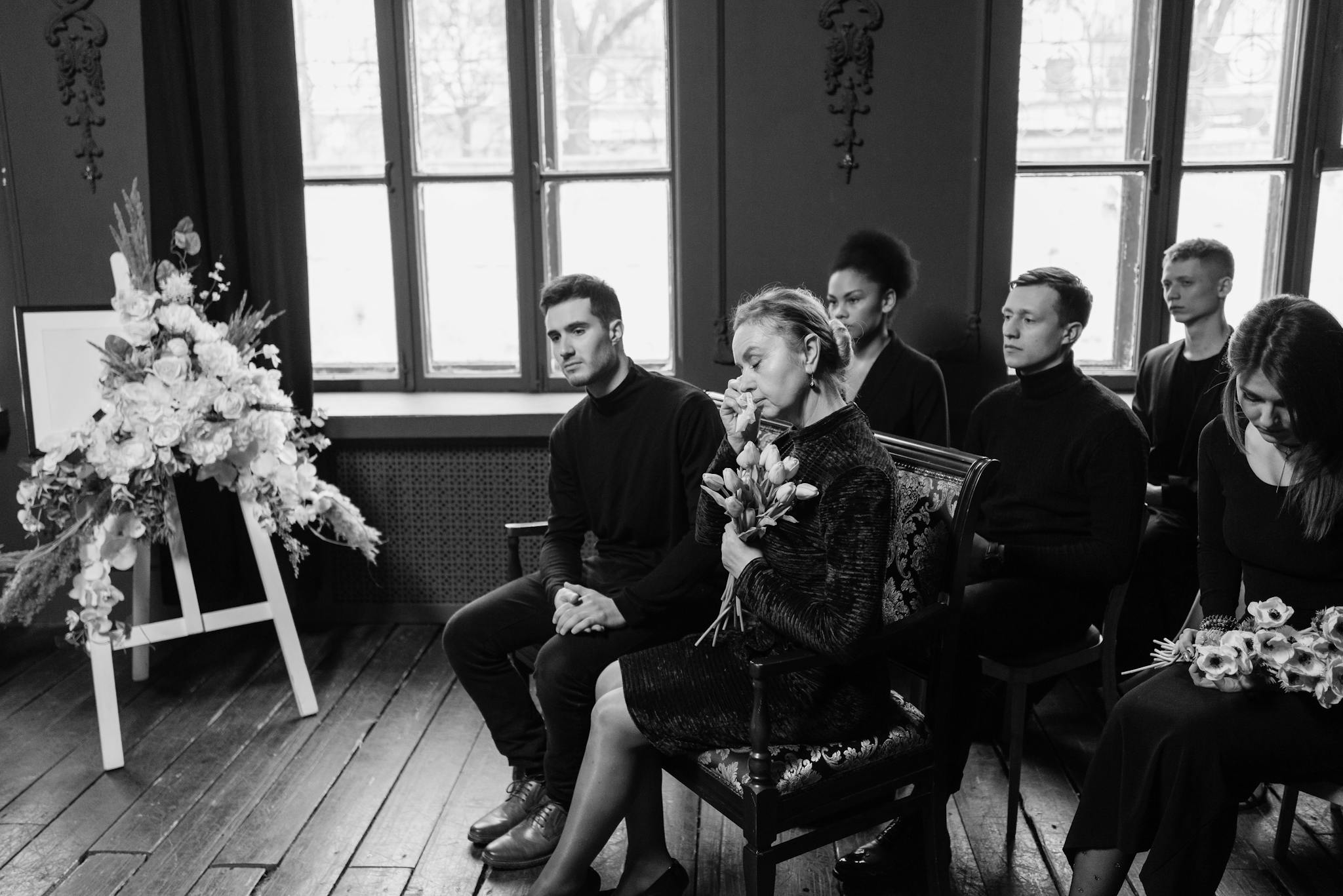 Grieving family members gather at a funeral, displaying emotions and support.